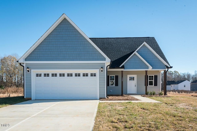 view of front of property with a garage, driveway, a front lawn, and roof with shingles