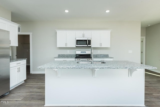 kitchen featuring appliances with stainless steel finishes, a sink, a breakfast bar area, and dark wood-style floors