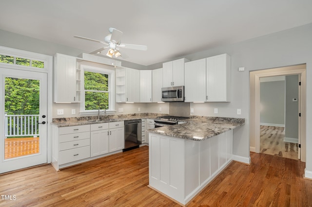 kitchen featuring light wood-type flooring, appliances with stainless steel finishes, white cabinetry, sink, and ceiling fan