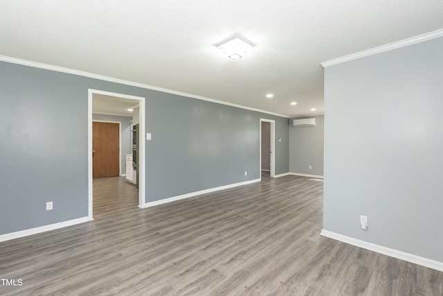 unfurnished room featuring a wall mounted air conditioner, a textured ceiling, crown molding, and hardwood / wood-style floors