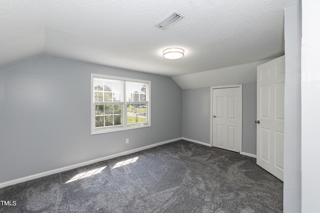 additional living space featuring vaulted ceiling, dark carpet, and a textured ceiling