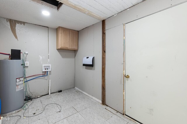 washroom featuring electric water heater, washer hookup, light tile patterned flooring, and cabinets