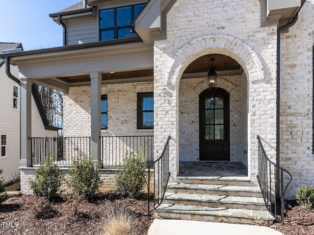 entrance to property with a porch and brick siding