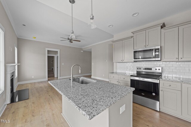 kitchen with appliances with stainless steel finishes, tasteful backsplash, sink, a kitchen island with sink, and ceiling fan