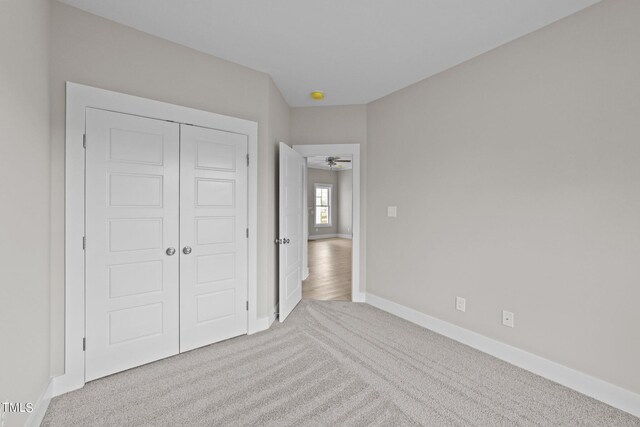 unfurnished bedroom featuring light colored carpet and a closet