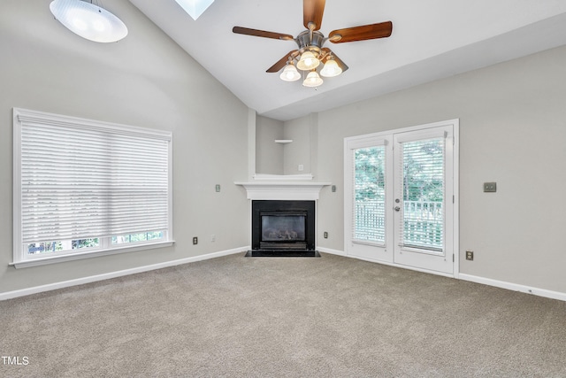 unfurnished living room featuring lofted ceiling with skylight, carpet floors, and ceiling fan