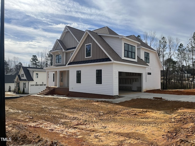 view of front facade featuring a standing seam roof, an attached garage, a shingled roof, board and batten siding, and metal roof