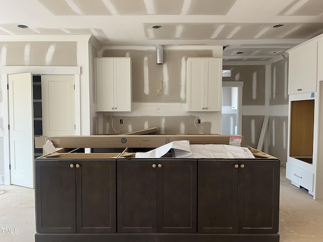 kitchen with white cabinets, a center island, and concrete floors