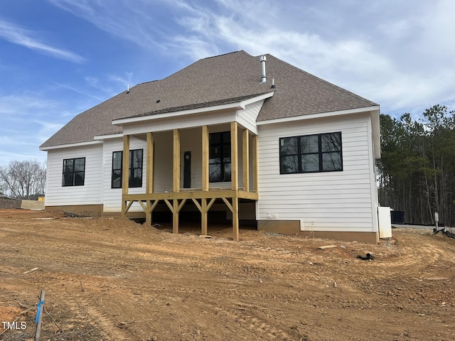 back of house featuring roof with shingles