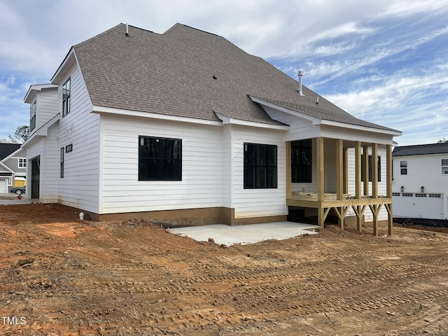 back of property with a patio and roof with shingles