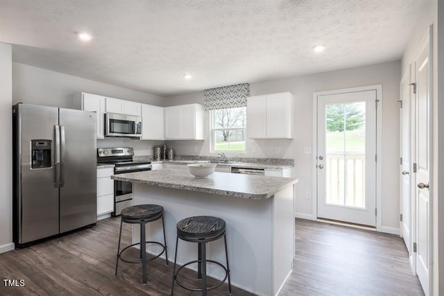 kitchen with white cabinetry, a kitchen island, a kitchen breakfast bar, and appliances with stainless steel finishes