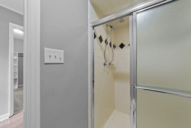 bathroom featuring hardwood / wood-style flooring, crown molding, and an enclosed shower