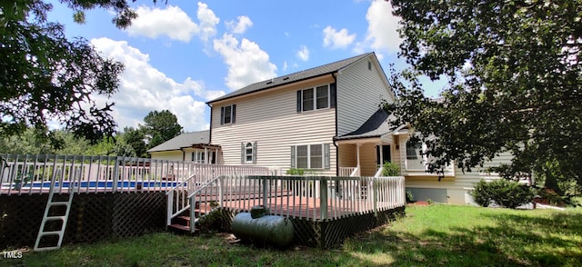 back of house featuring a pool side deck and a lawn