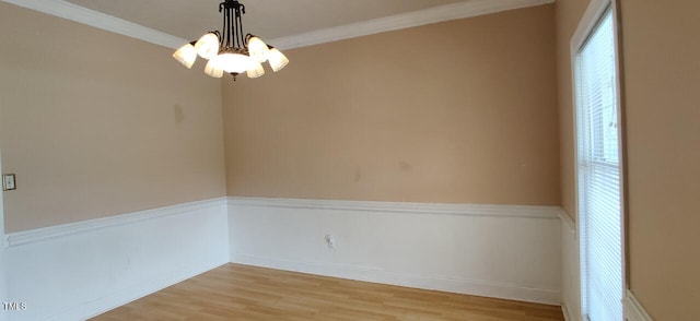 empty room with crown molding, a wealth of natural light, light hardwood / wood-style floors, and a notable chandelier