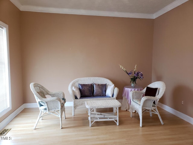 sitting room with crown molding and light hardwood / wood-style floors