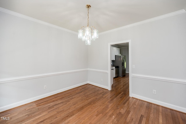 unfurnished room with wood-type flooring, a notable chandelier, and ornamental molding