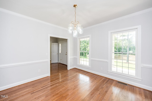 spare room with a notable chandelier, hardwood / wood-style flooring, and crown molding