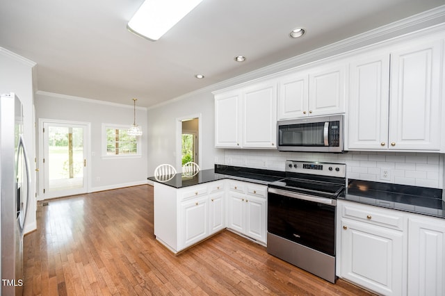 kitchen featuring crown molding, light hardwood / wood-style flooring, kitchen peninsula, appliances with stainless steel finishes, and decorative backsplash