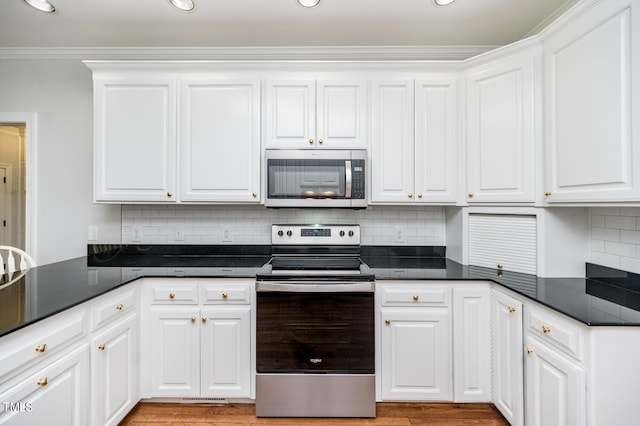 kitchen featuring appliances with stainless steel finishes, light hardwood / wood-style flooring, white cabinets, and backsplash