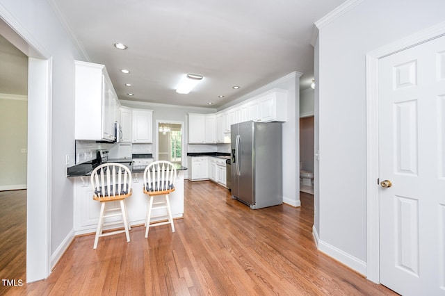 kitchen with light hardwood / wood-style floors, white cabinets, stainless steel fridge, and a breakfast bar