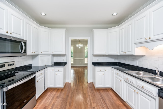 kitchen featuring appliances with stainless steel finishes, backsplash, crown molding, and light wood-type flooring