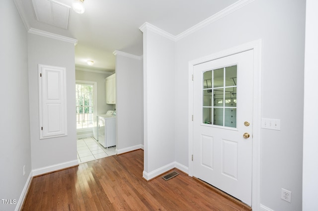 tiled foyer entrance featuring crown molding and washer and dryer