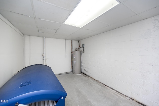 miscellaneous room featuring electric water heater, a paneled ceiling, and concrete flooring