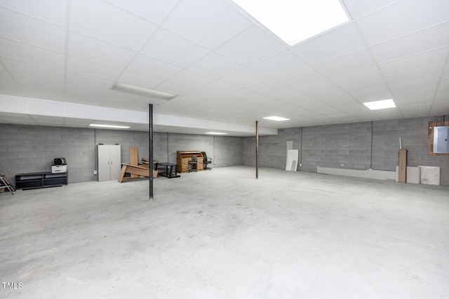 basement with a drop ceiling and electric panel