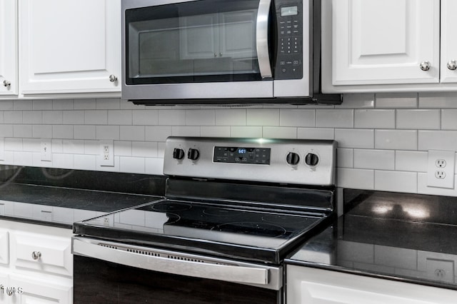 kitchen with appliances with stainless steel finishes, white cabinets, and backsplash