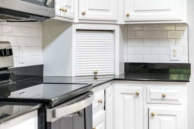 kitchen with stainless steel electric range oven, white cabinets, and backsplash