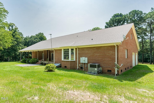 rear view of property with central air condition unit and a yard