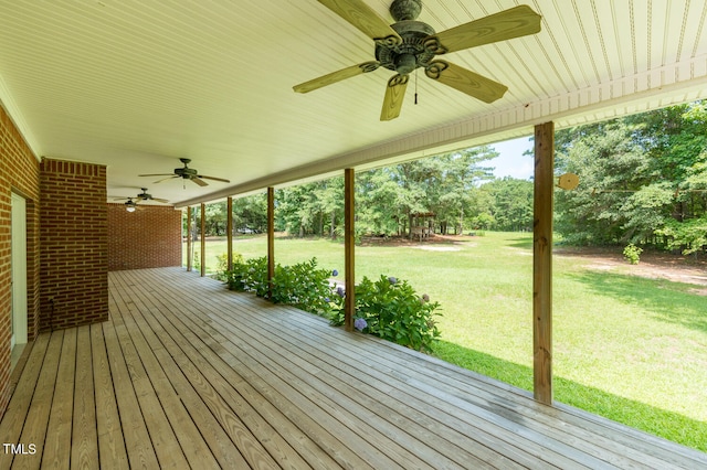 wooden terrace featuring ceiling fan and a lawn