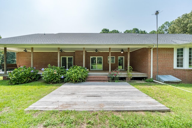 back of property with ceiling fan, a lawn, and a deck