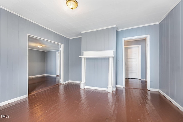 unfurnished living room featuring ornamental molding, baseboards, and wood finished floors