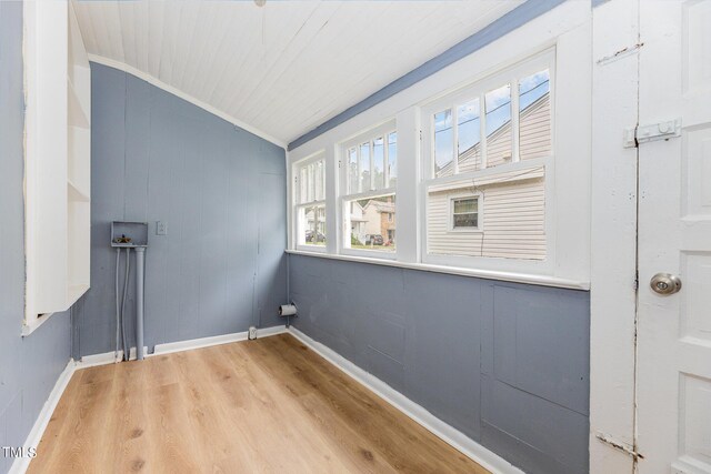 empty room featuring lofted ceiling, crown molding, and light wood-type flooring