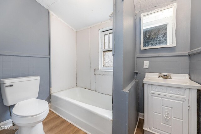 full bathroom with  shower combination, hardwood / wood-style floors, tile walls, toilet, and vanity