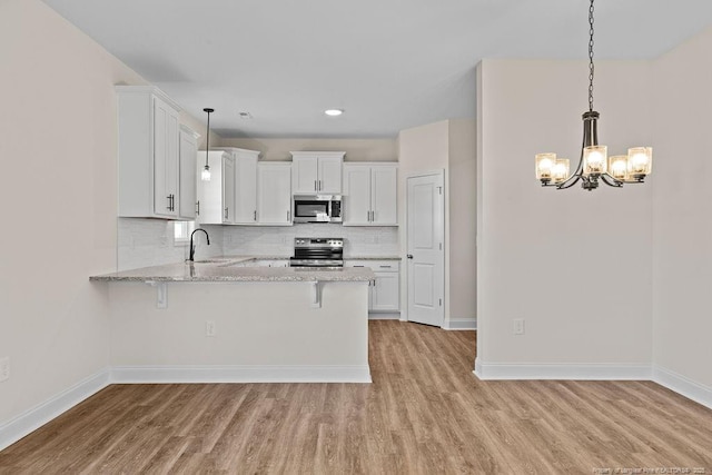 kitchen with kitchen peninsula, white cabinets, hanging light fixtures, and appliances with stainless steel finishes