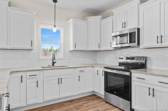 kitchen featuring decorative light fixtures, white cabinetry, sink, and appliances with stainless steel finishes