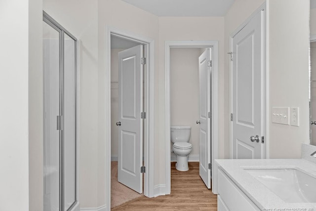 bathroom with vanity, toilet, a shower with shower door, and wood-type flooring