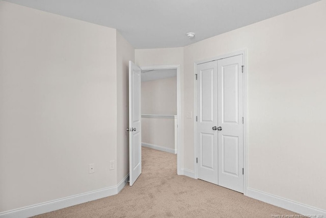 unfurnished bedroom featuring light colored carpet and a closet