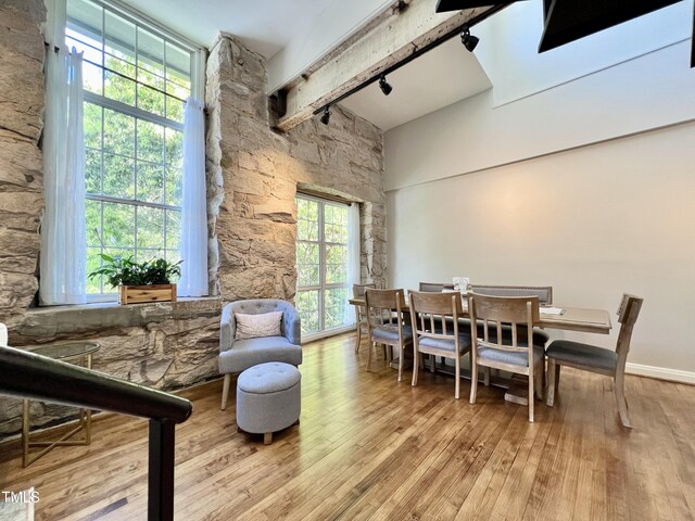 dining area with beam ceiling and light wood-type flooring