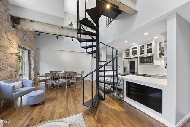 interior space featuring a towering ceiling, dark hardwood / wood-style flooring, beamed ceiling, and sink