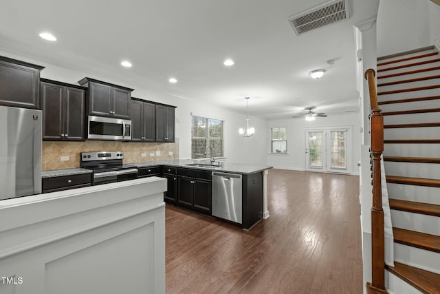 kitchen featuring sink, decorative light fixtures, stainless steel appliances, light stone countertops, and backsplash