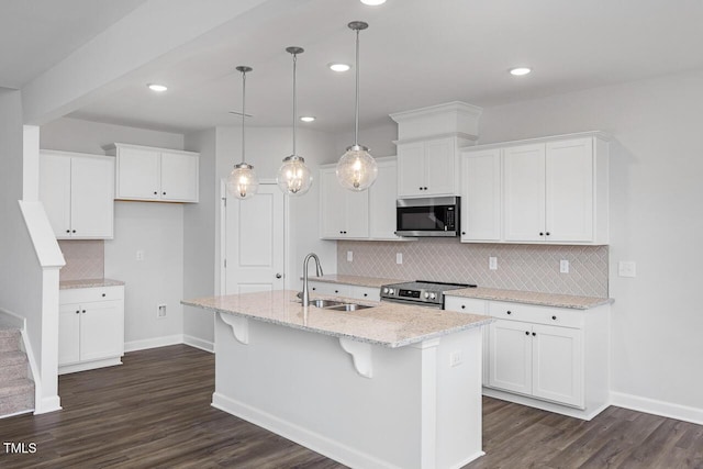 kitchen with stainless steel appliances, white cabinetry, hanging light fixtures, and a center island with sink