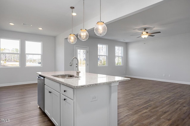 kitchen with light stone countertops, pendant lighting, white cabinets, sink, and a kitchen island with sink