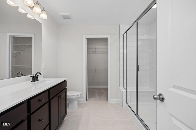 bathroom with vanity, a shower with shower door, tile patterned floors, and toilet