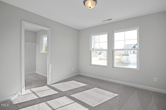 unfurnished bedroom featuring a spacious closet, a closet, and light carpet