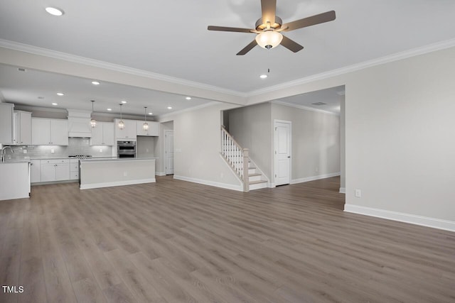 unfurnished living room featuring wood finished floors, recessed lighting, baseboards, ceiling fan, and stairs