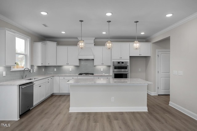 kitchen featuring crown molding, white cabinets, appliances with stainless steel finishes, and a sink