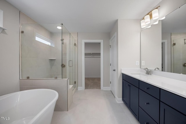 full bathroom featuring a walk in closet, a stall shower, a freestanding bath, and vanity